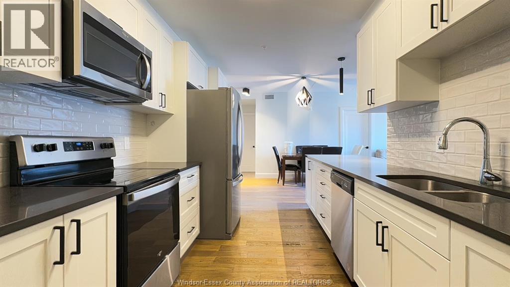 A kitchen with white cabinets and black countertops.