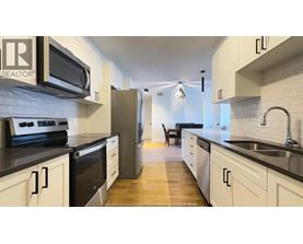 A kitchen with white cabinets and black countertops.