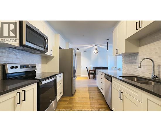 A kitchen with white cabinets and black countertops.