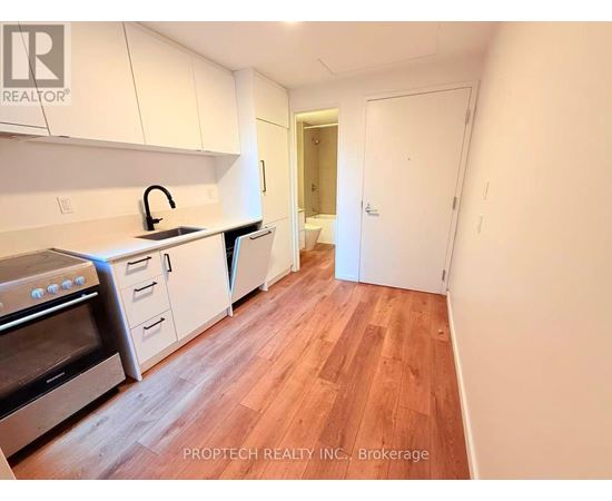 A kitchen with white cabinets and wood flooring.