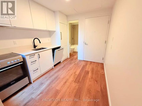 A kitchen with white cabinets and wood flooring.