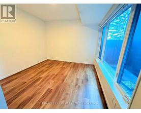 A room with wooden flooring and a window showing trees outside.