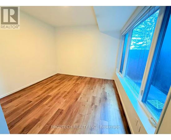 A room with wooden flooring and a window showing trees outside.