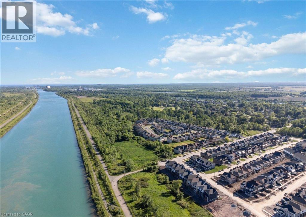 A river flows through a green landscape next to a housing development.