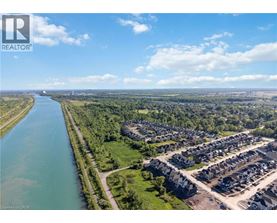 A river flows through a green landscape next to a housing development.
