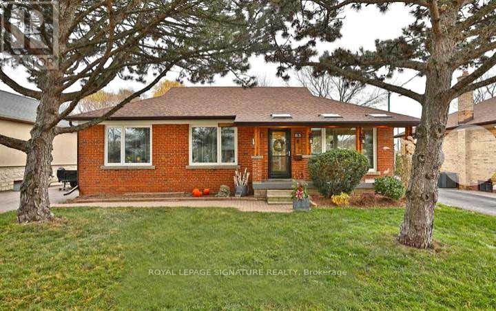 A brick house with a front yard and trees.