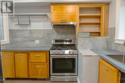 A kitchen with a stove top oven and wooden cabinets.