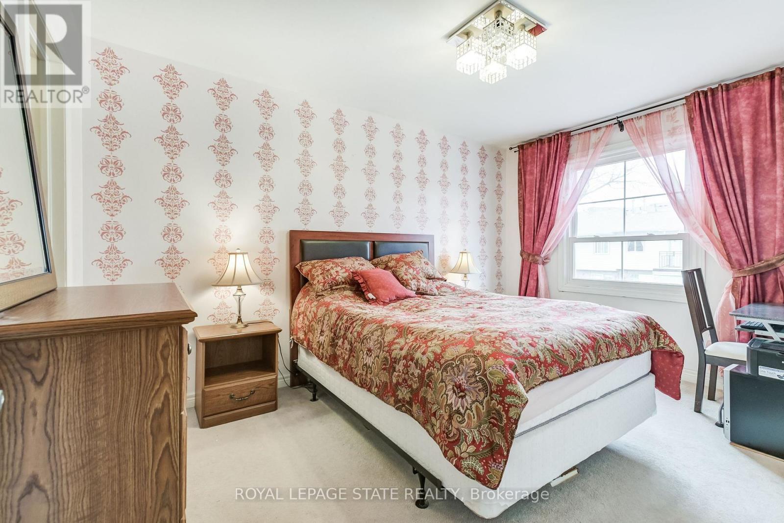 A bedroom with a bed, nightstand, and chair.