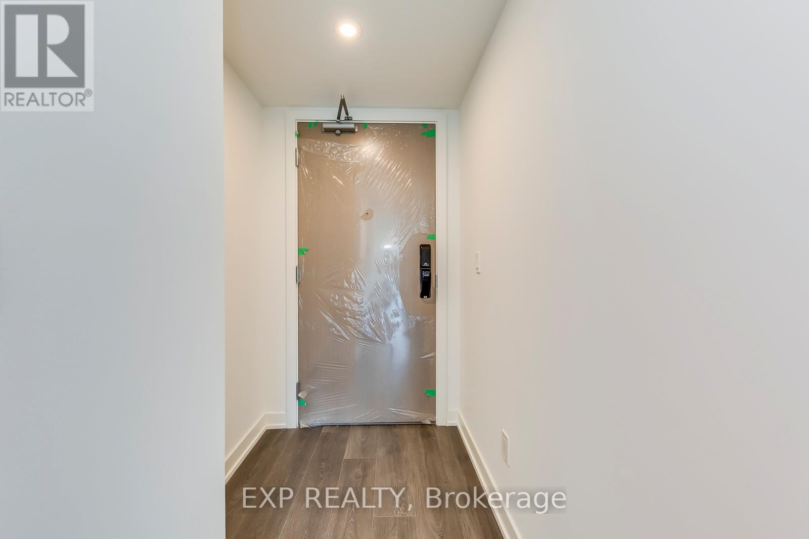 A room with a door covered in plastic and a REALTOR® logo on the wall.