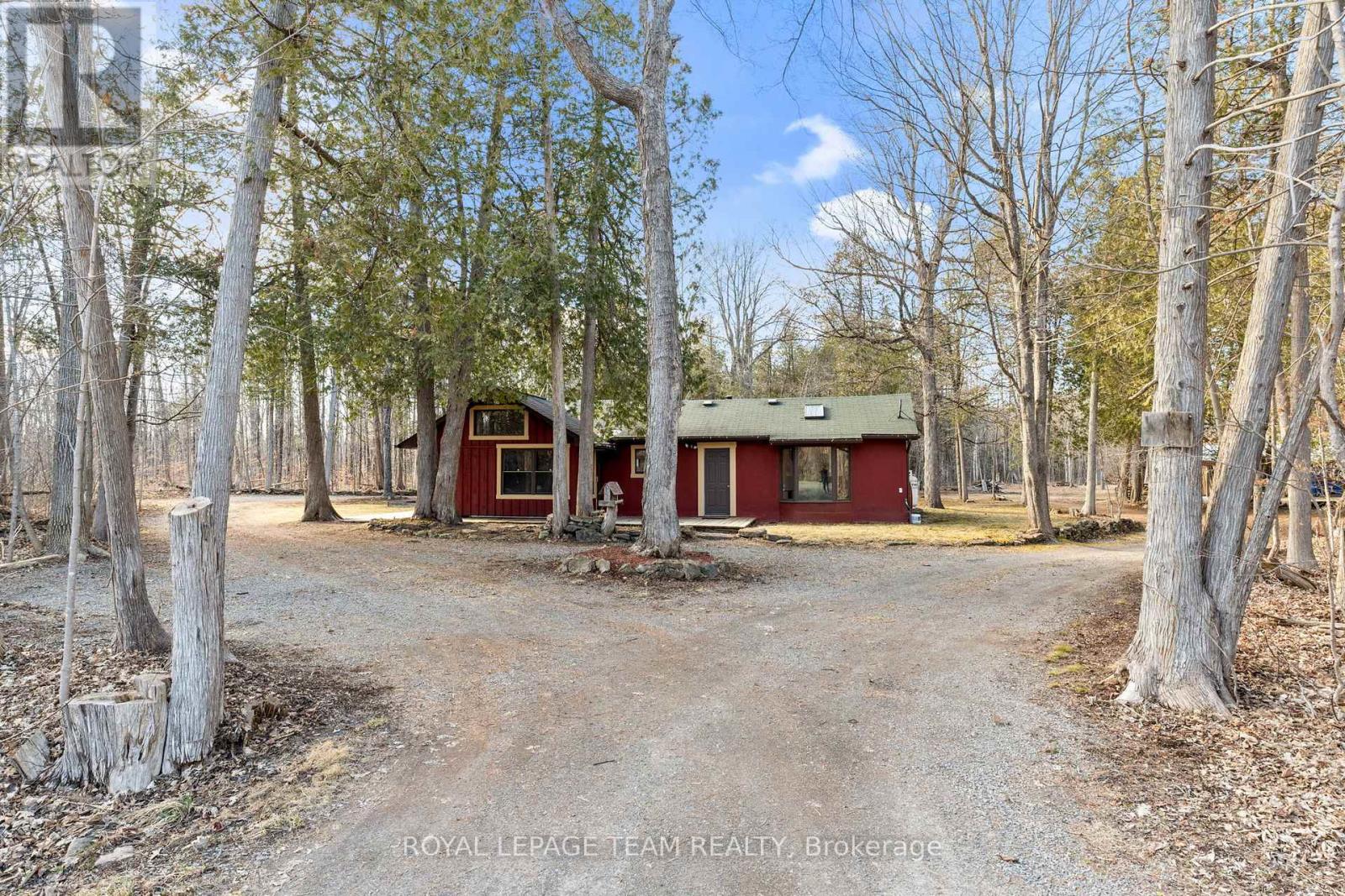 A red house is surrounded by trees in a wooded area.