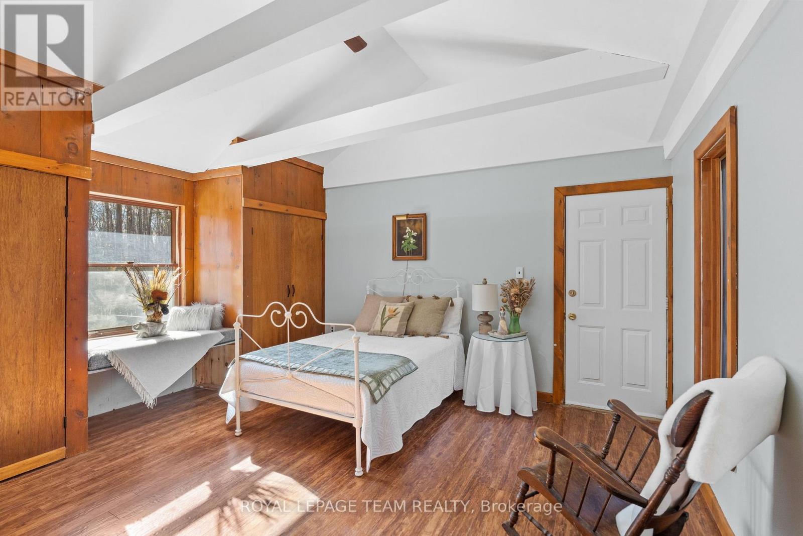 A bedroom with a bed, a table, and a chair.