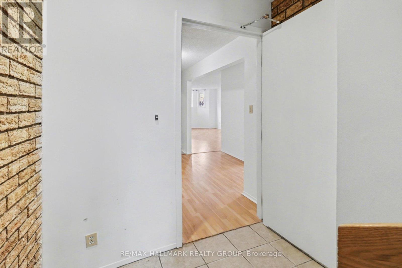 A hallway with a brick wall on the left and a white door on the right.