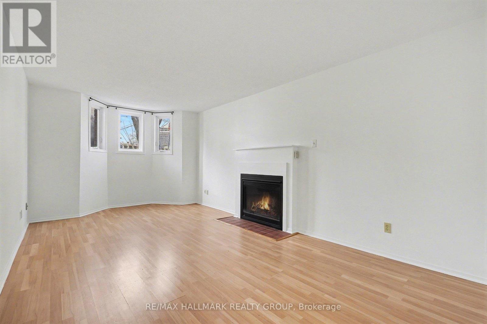A spacious room with a fireplace and wooden flooring.