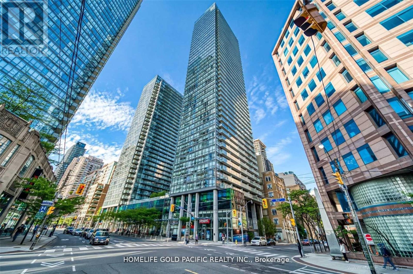 A tall glass building stands in the middle of a city intersection.