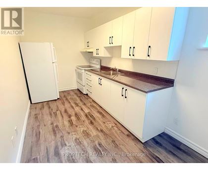 A kitchen with white cabinets and a white refrigerator.