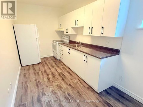 A kitchen with white cabinets and a white refrigerator.