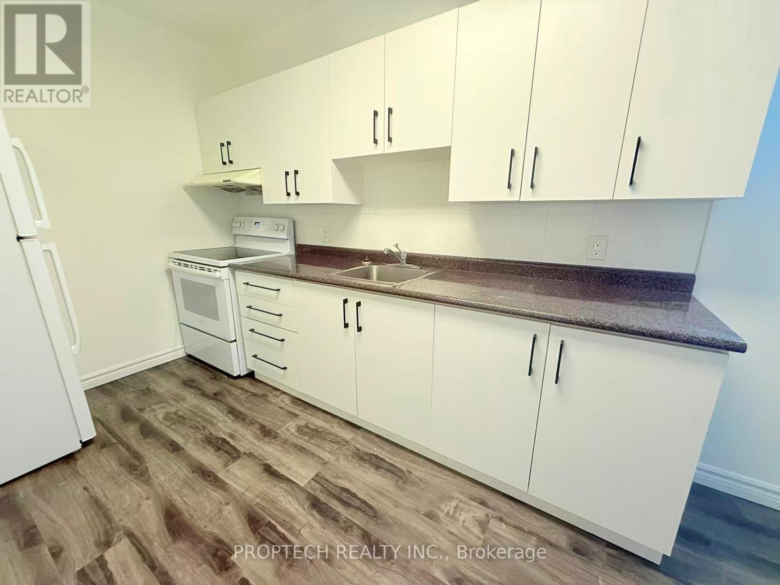A kitchen with white cabinets and a wooden floor.