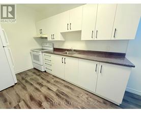 A kitchen with white cabinets and a wooden floor.