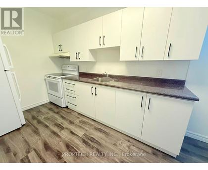 A kitchen with white cabinets and a wooden floor.