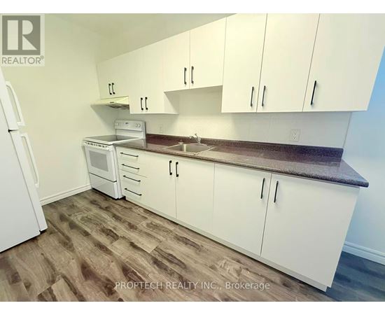 A kitchen with white cabinets and a wooden floor.