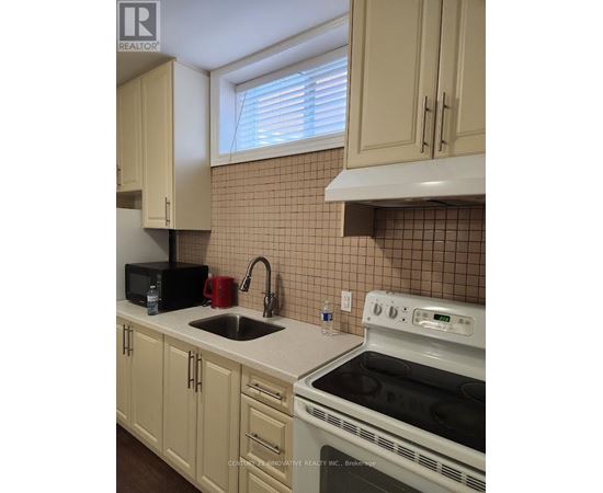 A kitchen with a white stove top oven and a black microwave.