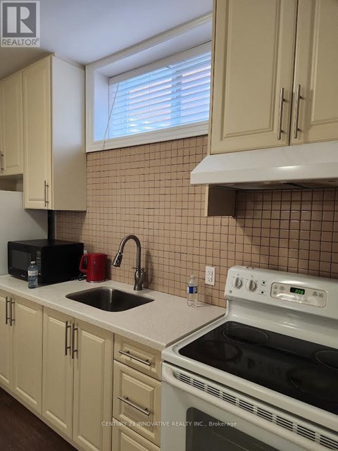 A kitchen with a white stove top oven and a black microwave.