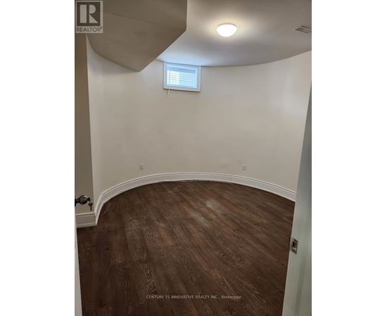 A room with wooden flooring and a window with blinds.