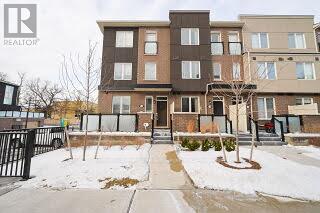 A brown and beige apartment building with a black fence in front.