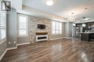 A spacious living room with a stone fireplace and hardwood floors.