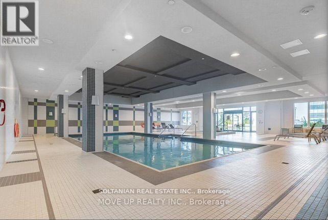 A large indoor swimming pool with a tiled floor and a high ceiling.