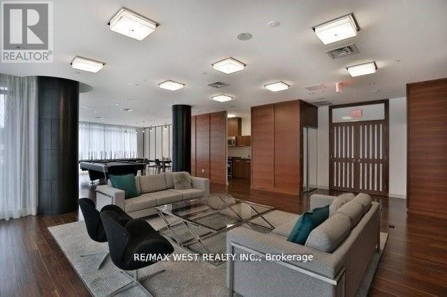 A spacious living room with a large grey sofa and a glass table.