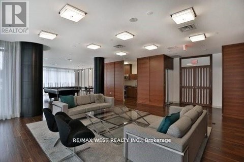 A spacious living room with a large grey sofa and a glass table.