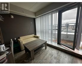 A room with a couch, a table, and a window with blinds.