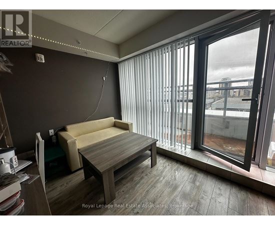 A room with a couch, a table, and a window with blinds.