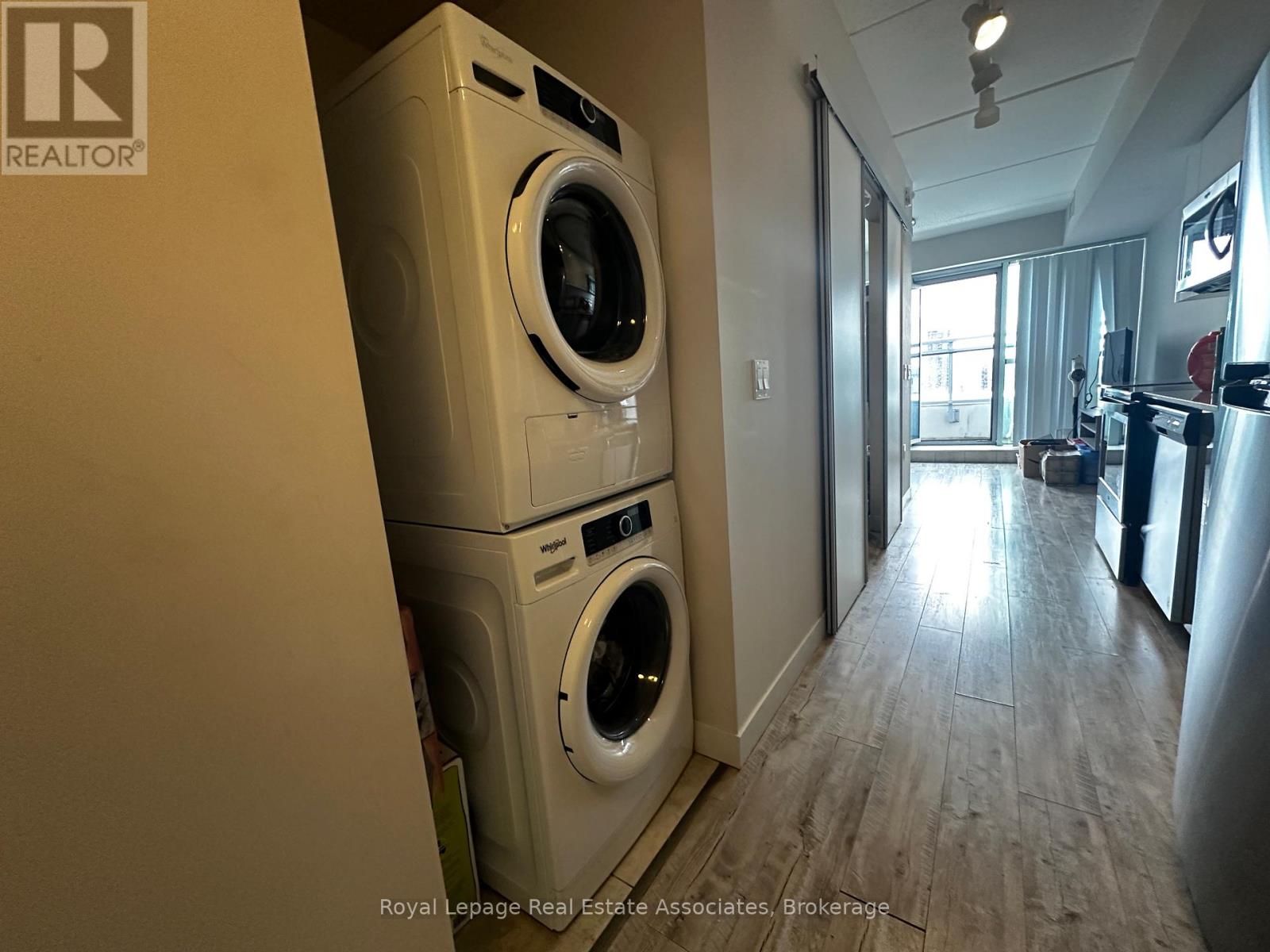 A Royal LePage Real Estate Associates brokerage logo is on a wall in a room with a washer and dryer stacked on top of each other.