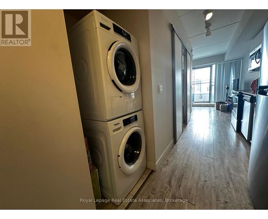 A Royal LePage Real Estate Associates brokerage logo is on a wall in a room with a washer and dryer stacked on top of each other.