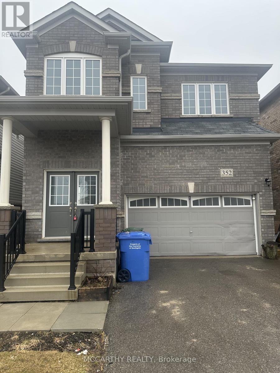 A two-story house with a garage and a blue trash bin in front.