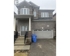 A two-story house with a garage and a blue trash bin in front.