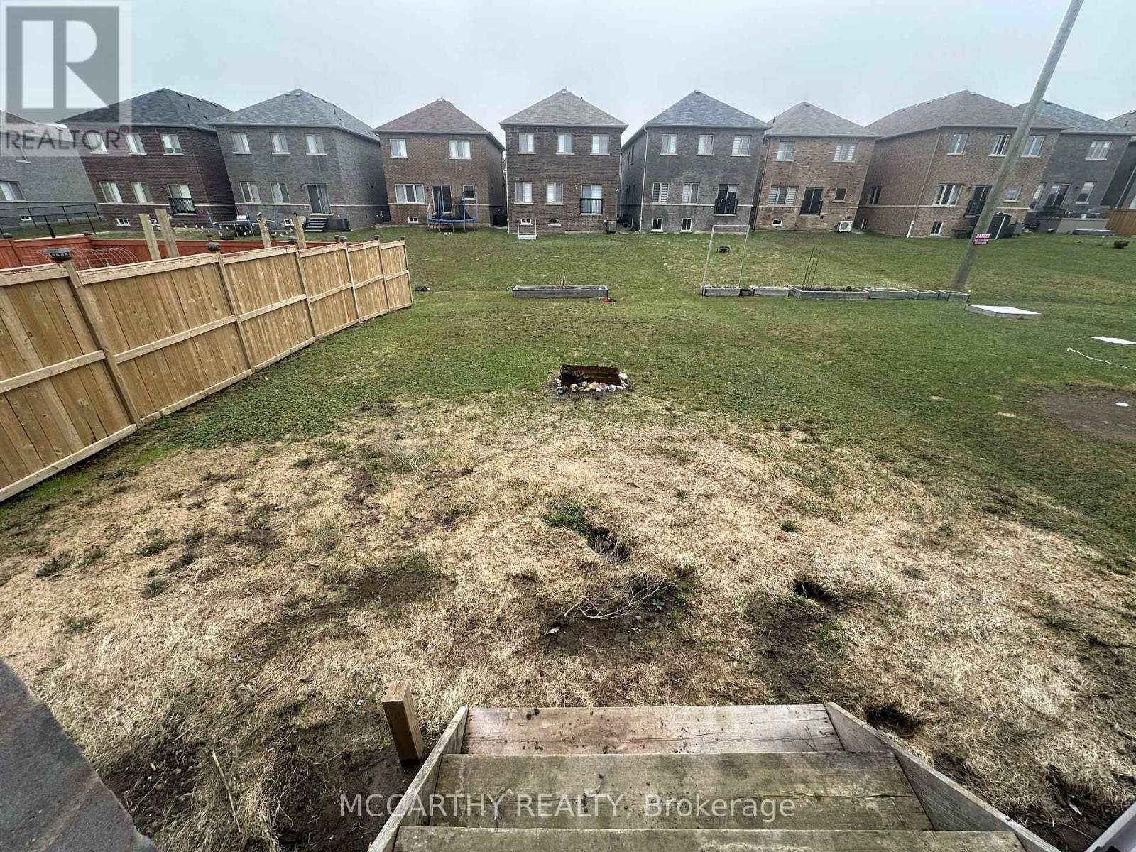 A grassy area in front of a row of houses with a wooden fence on the left side.