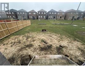 A grassy area in front of a row of houses with a wooden fence on the left side.
