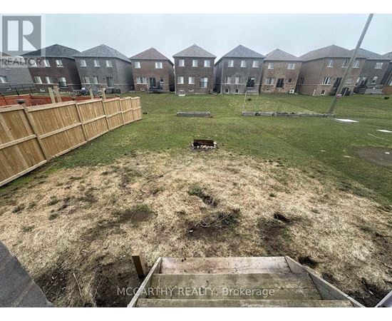 A grassy area in front of a row of houses with a wooden fence on the left side.
