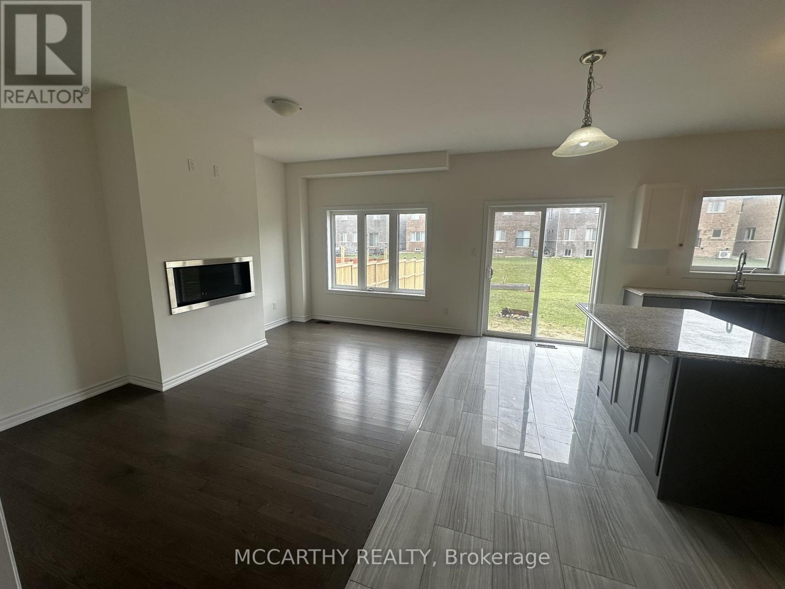 A spacious living room with a television and sliding glass doors leading to a backyard.