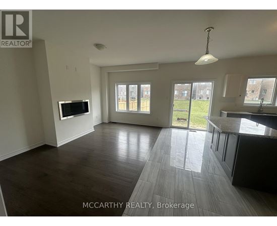 A spacious living room with a television and sliding glass doors leading to a backyard.