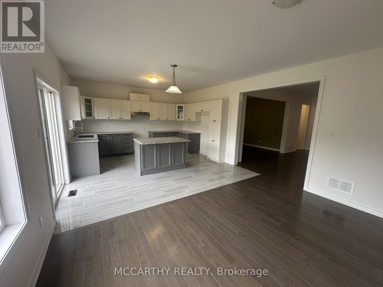 A spacious room with a kitchen area and a dining table.