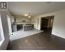 A spacious room with a kitchen area and a dining table.