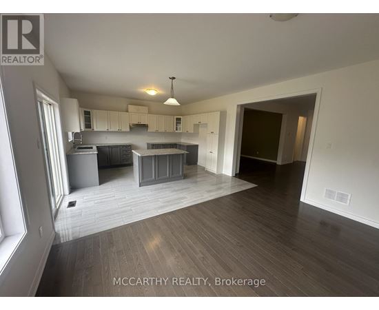 A spacious room with a kitchen area and a dining table.