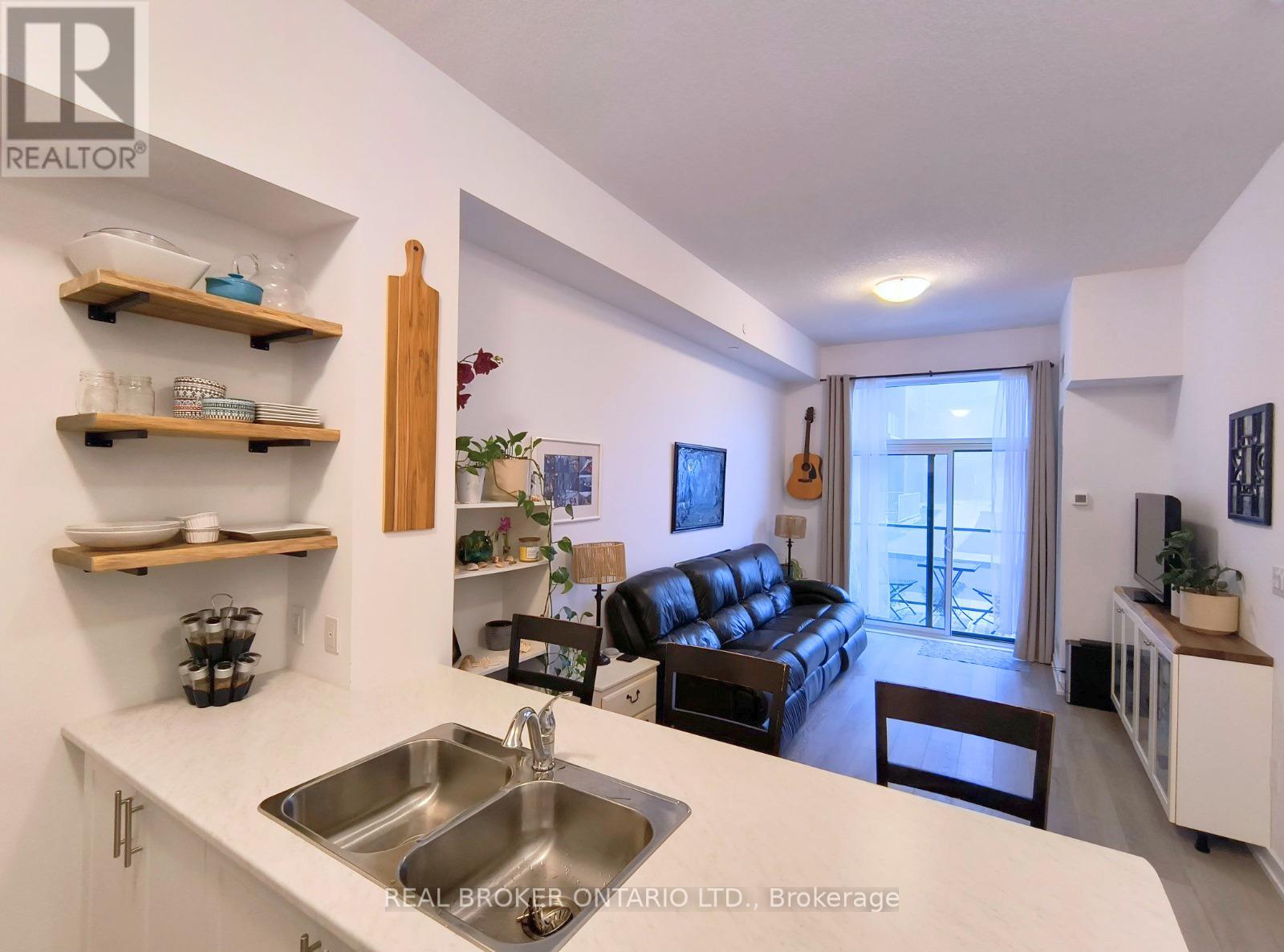 A kitchen with a sink and a couch in the background.
