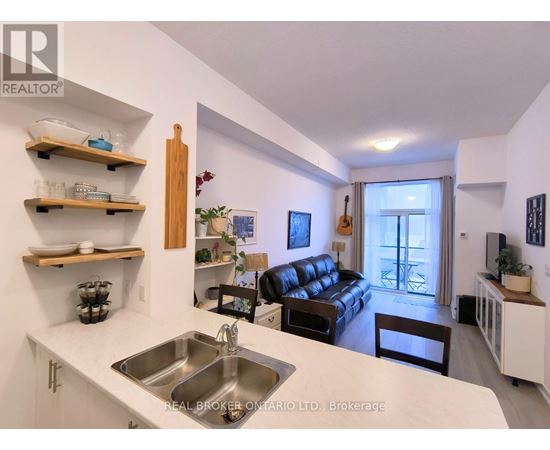 A kitchen with a sink and a couch in the background.
