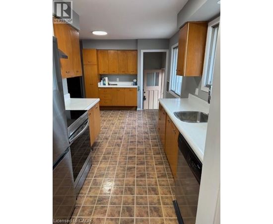 A kitchen with brown cabinets and tile flooring.