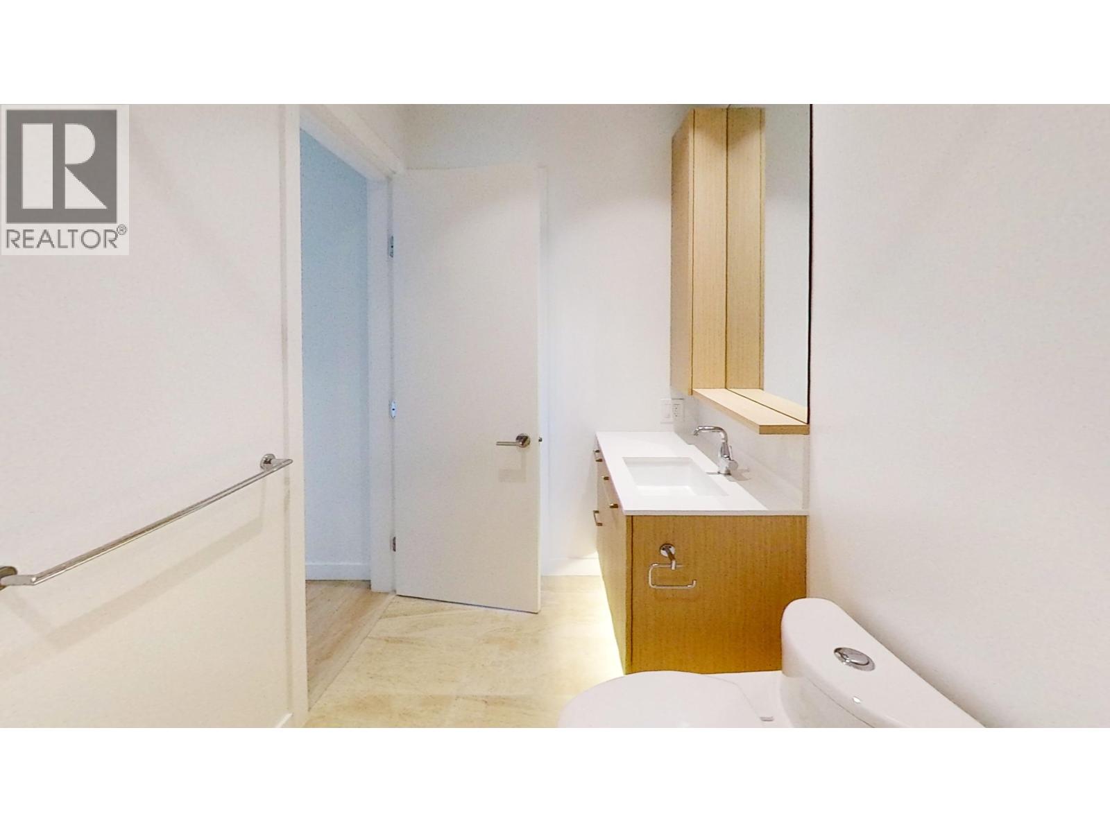 A bathroom with a toilet, sink, and mirror.